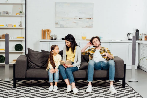 Handsome Man Holding Remote Controller Wife Reading Book Looking Daughter — Stock Photo, Image