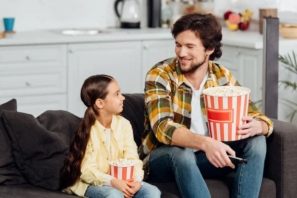 Szczęśliwy Człowiek Patrząc Cute Córki Trzymając Wiadro Popcorn Pilota Zdalnego — Zdjęcie stockowe