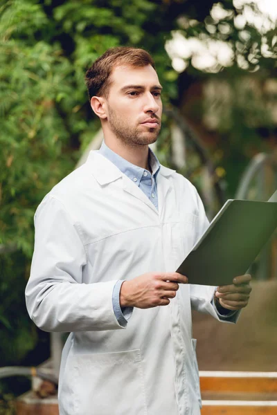 Serious Scientist White Coat Holding Folder Green Orangery — Stock Photo, Image