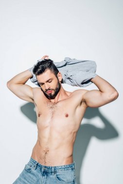 yakışıklı ve kaslı adam beyaz ayakta iken t-shirt kapalı alarak 