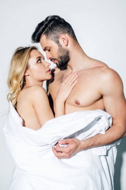 yakışıklı gömleksiz adam battaniye tutan ve beyaz çıplak kız bakıyor 