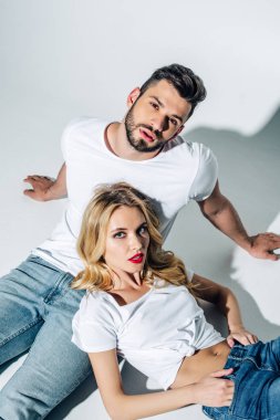 yakışıklı sakallı adam oturan ve beyaz ceplerinde elleri ile çekici sarışın kız yakın kameraya bakarak havai görünümü 