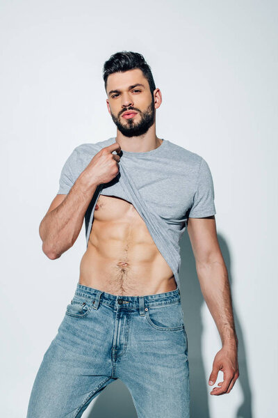 красивый мускулистый мужчина, смотрящий в камеру, стоя на белом
 