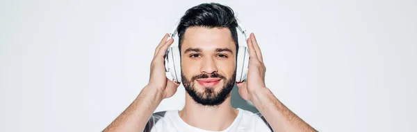 Plano Panorámico Hombre Alegre Tocando Auriculares Mientras Escucha Música Sonriendo —  Fotos de Stock