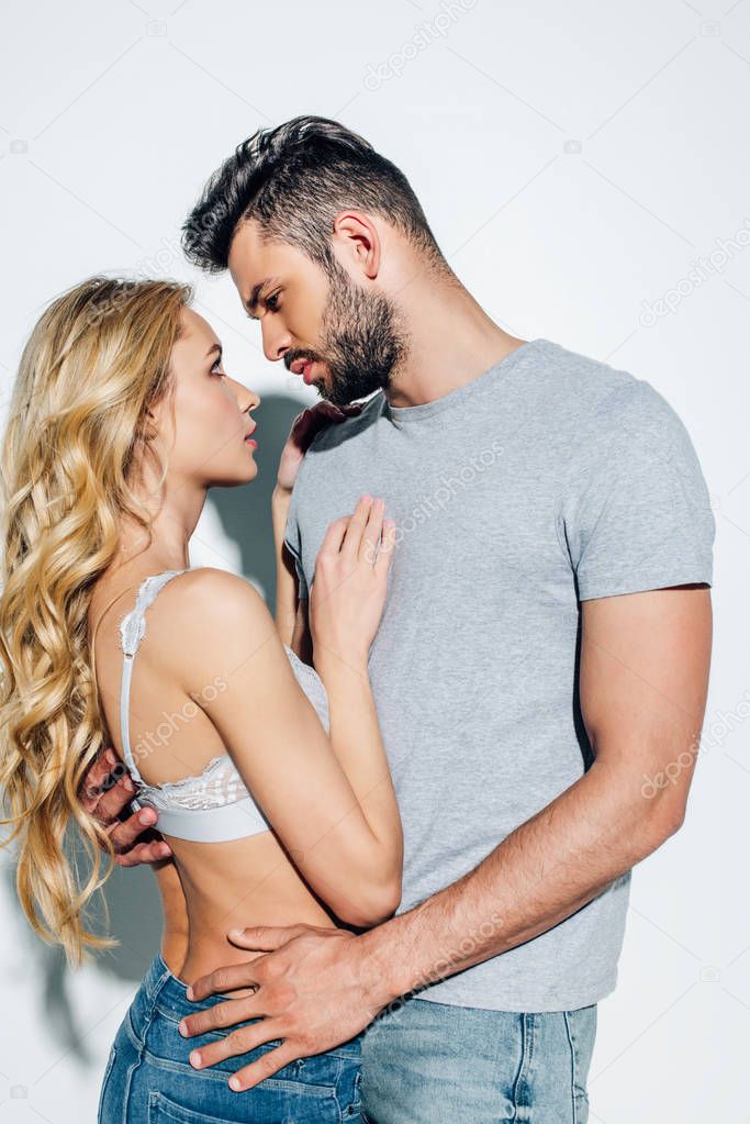 handsome man looking at attractive blonde girl in lace bra on white 