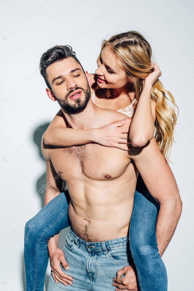 handsome man piggybacking cheerful blonde girl on white 