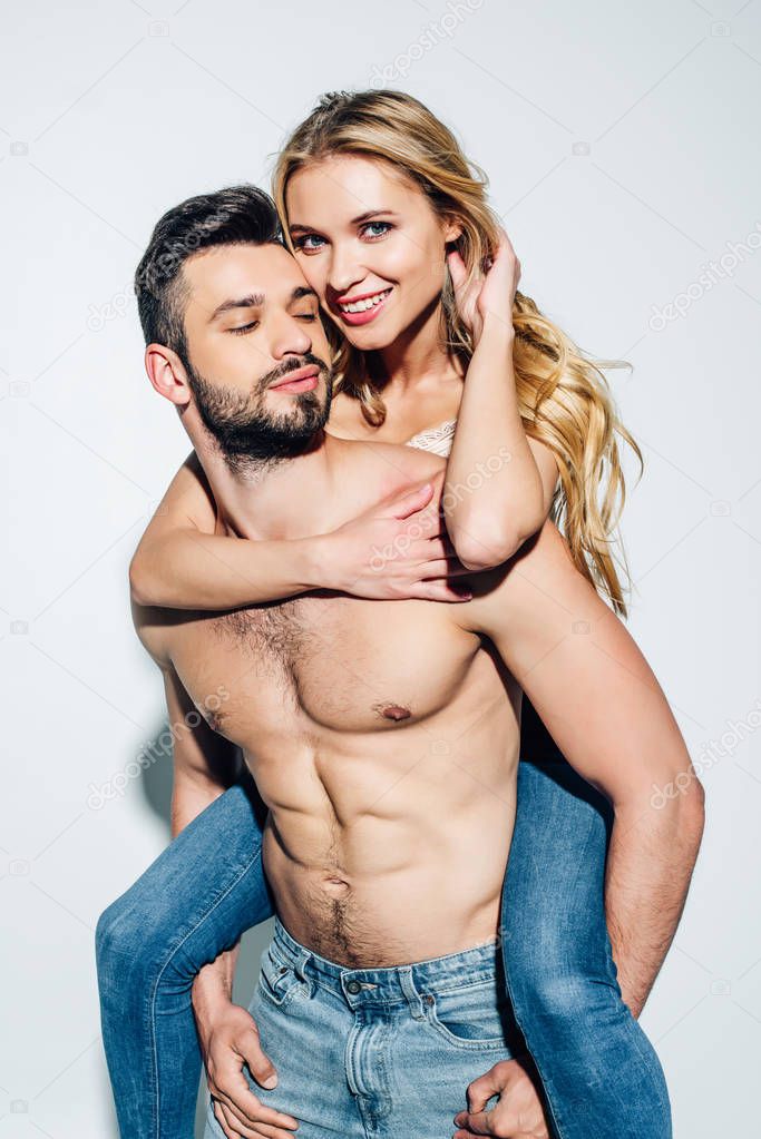 handsome man piggybacking happy blonde young woman on white 