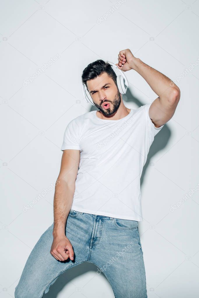 handsome man listening music in headphones and gesturing on white 