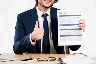 cropped view of cheerful recruiter showing thumb up and holding resume  clipart