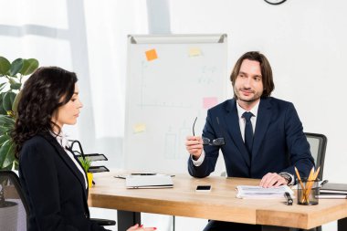 yakışıklı İşveren gözlük tutan ve ofiste çekici kadın bakıyor 