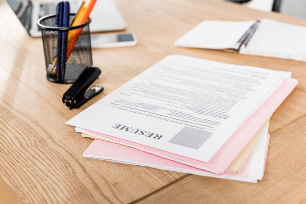 selective focus of resume near stapler and pen holder on table 
