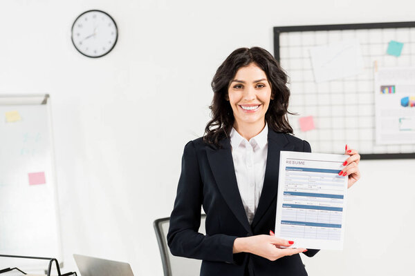 attractive and cheerful recruiter holding resume in office 