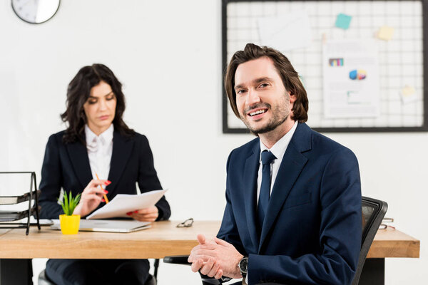selective focus of cheerful man looking at camera near attractive recruiter 