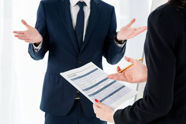 cropped view of woman holding resume and pencil near gesturing man 