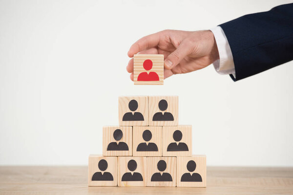 обрезанный вид человека говорящего деревянный куб из пирамиды на белом
