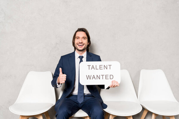 Счастливый рекрутер, сидящий на стуле и держащий в руках пузырь речи с талантом, хотел наклониться и показать большой палец вверх
