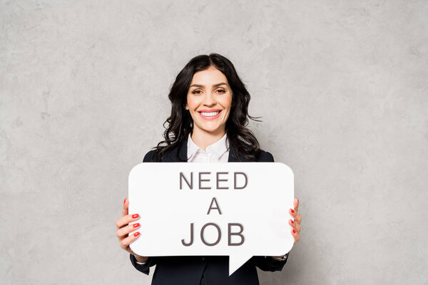 счастливая брюнетка женщина держа пузырь речи с талантом хотел надпись на сером
 