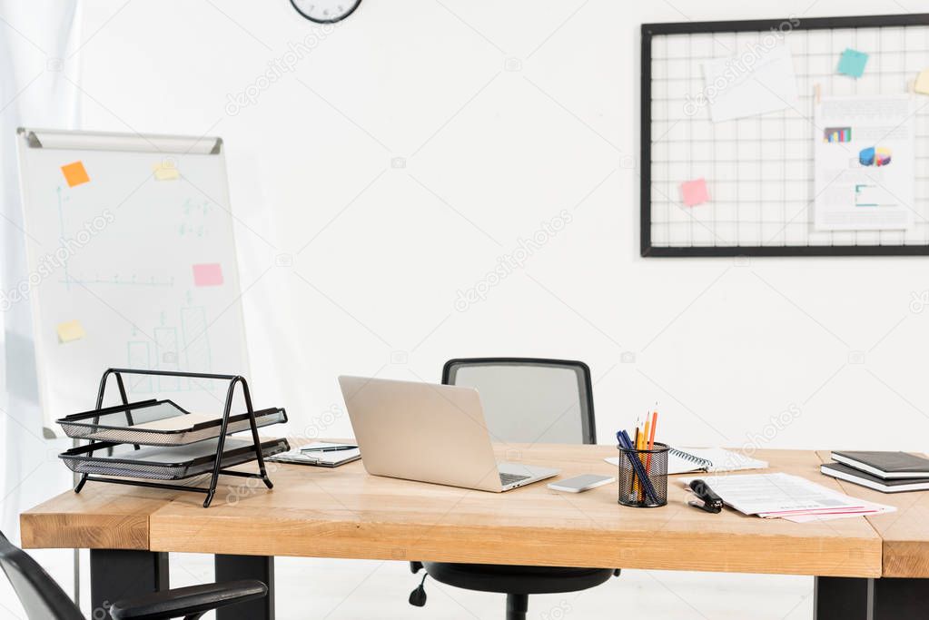 modern office with white board and laptop on wooden desk 