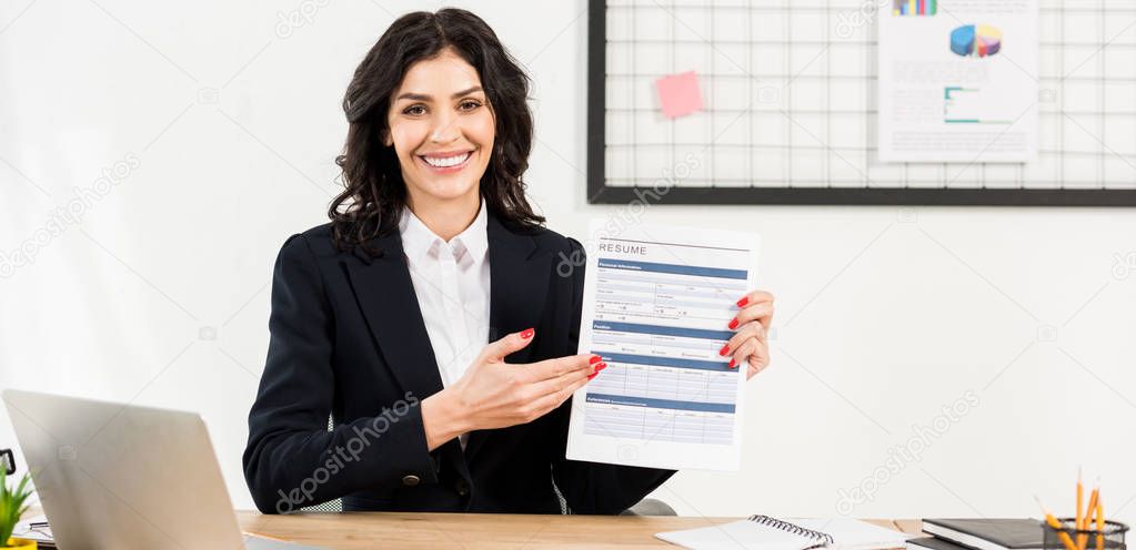 panoramic shot of cheerful recruiter holding resume and gesturing in office 