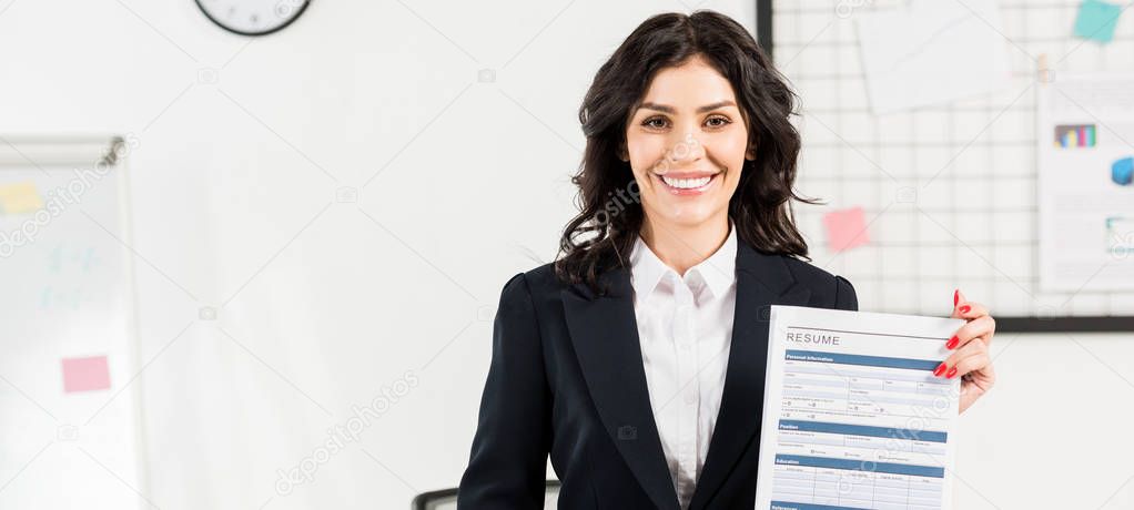 panoramic shot of cheerful recruiter holding resume in office 