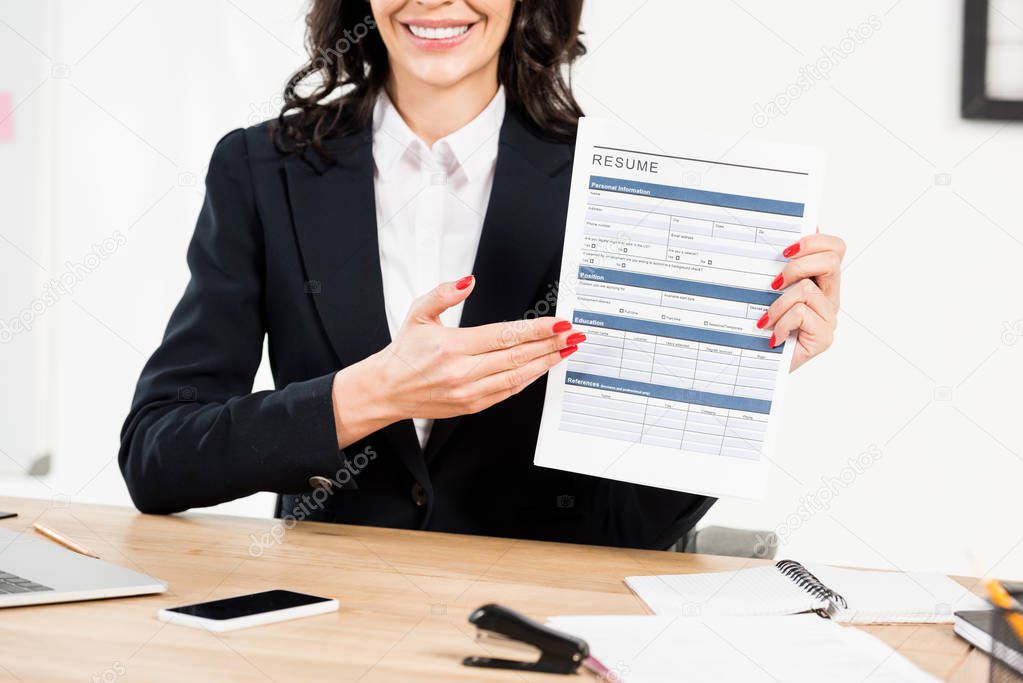 cropped view of cheerful woman gesturing while holding resume 
