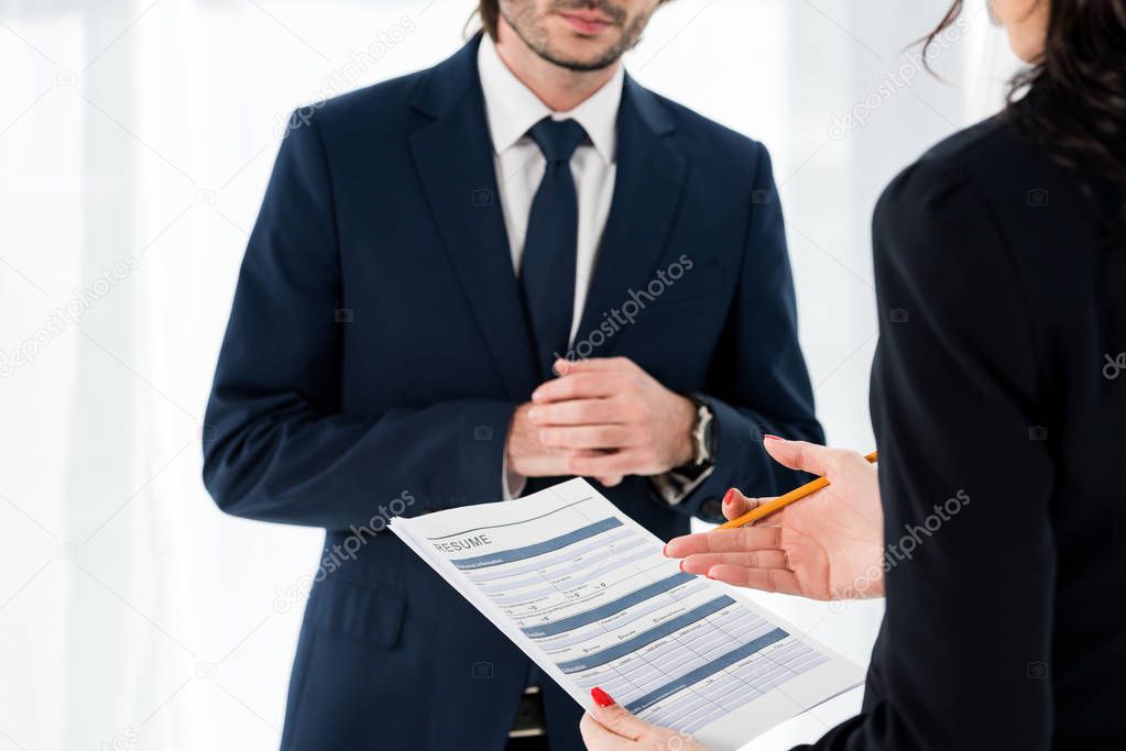 cropped view of woman holding resume and gesturing near man 