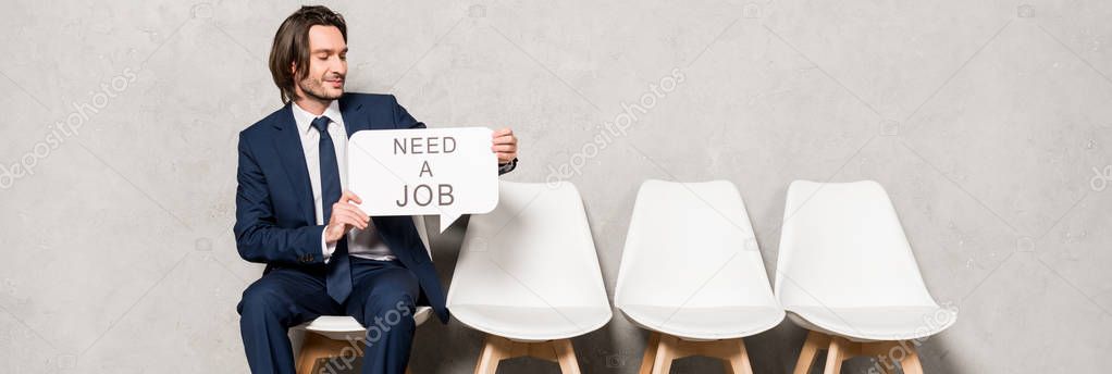 panoramic shot of happy employee holding speech bubble with need a job lettering 