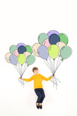 top view of happy kid holding colorful balloons and smiling on white  clipart
