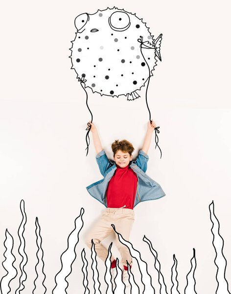 Вид сверху веселого малыша, держащего рыбу на белом
 