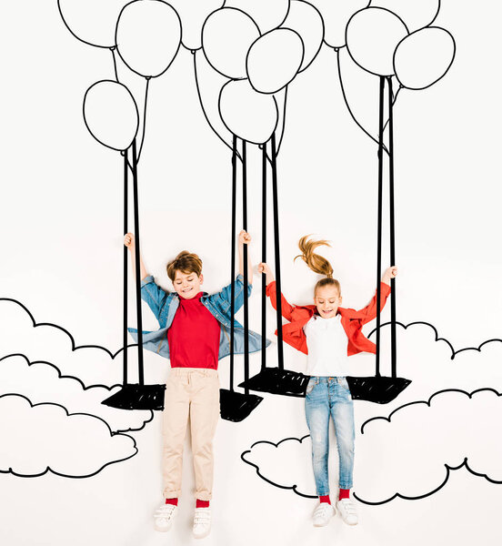 вид сверху веселых детей на качелях возле воздушных шаров и облаков на белом
 