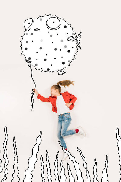 Вид сверху веселого ребенка, держащего в руках рыбу и улыбающегося на белом
 