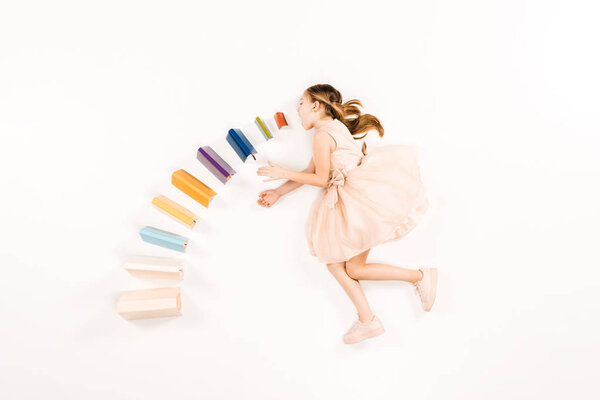 top view of cute kid in pink dress with open mouth near books on white 