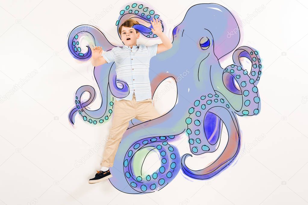 top view of scared kid gesturing near blue octopus with tentacles on white 