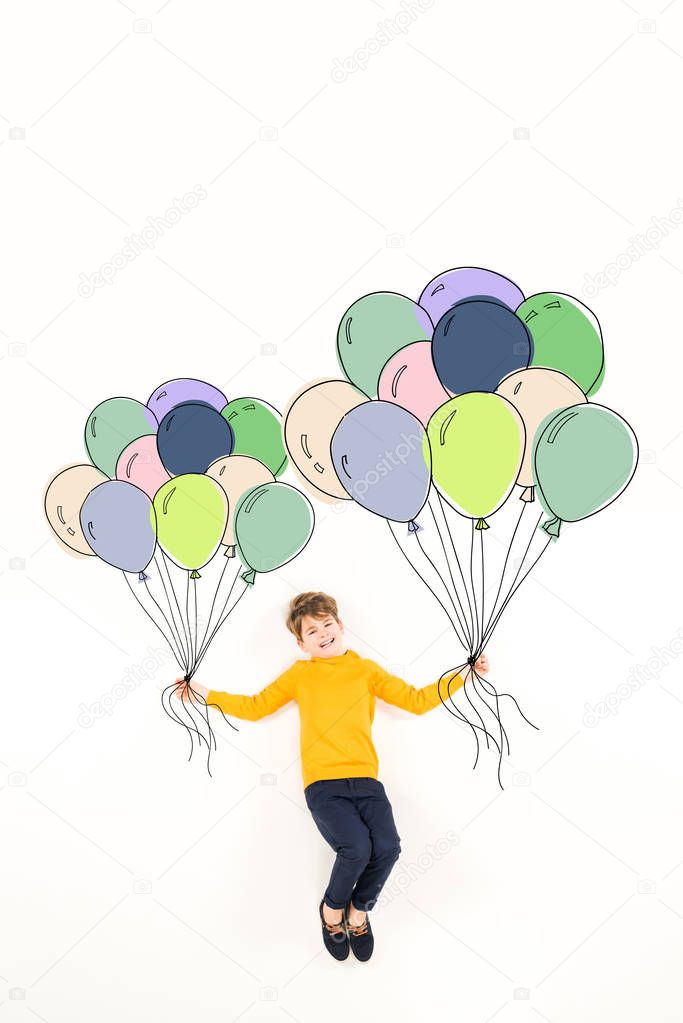 top view of happy kid holding colorful balloons and smiling on white 