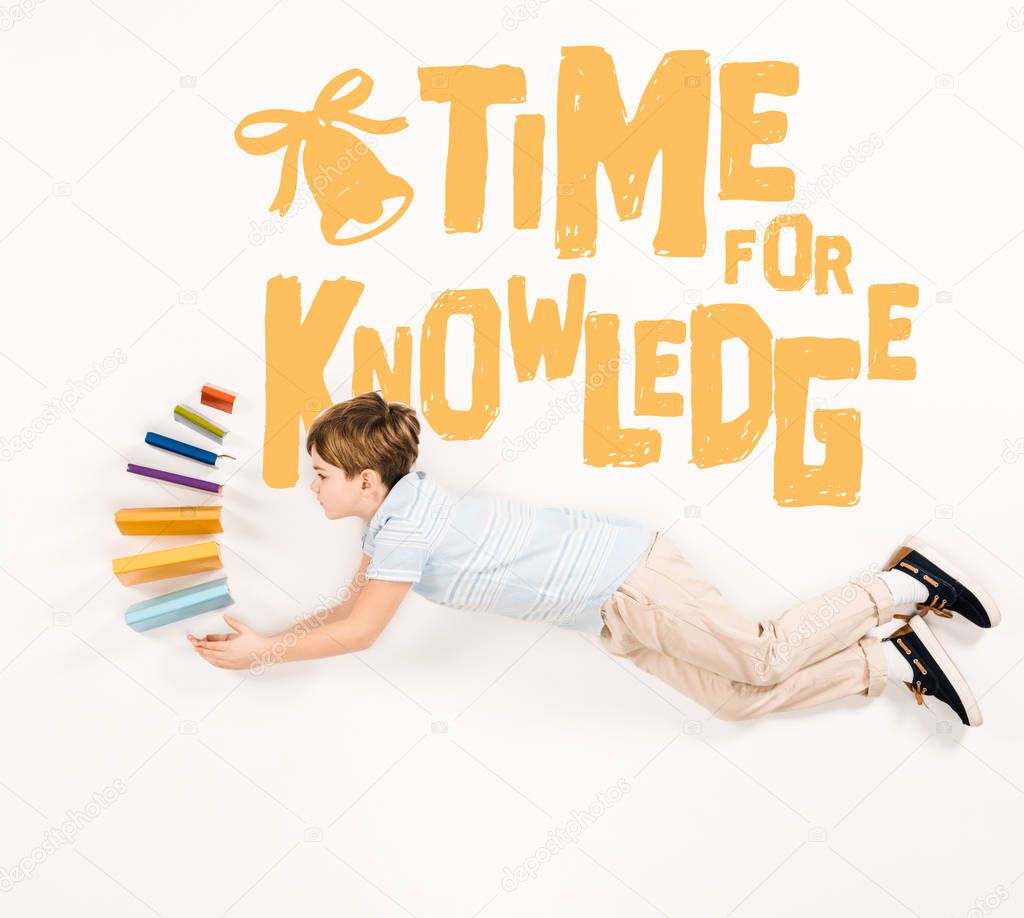 top view of kid holding books and flying near time for knowledge lettering on white