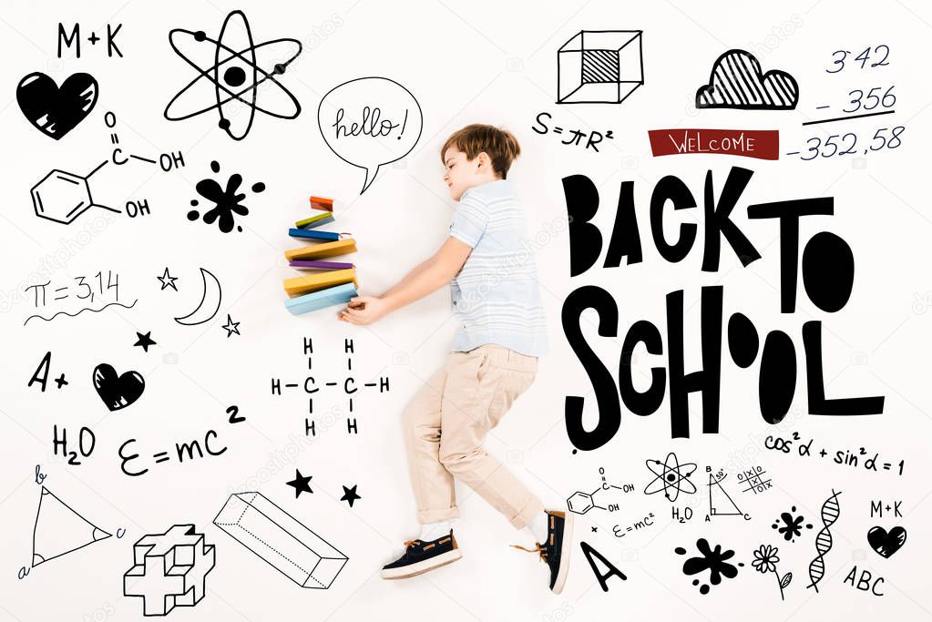top view of kid near colorful books and welcome back to school lettering on white