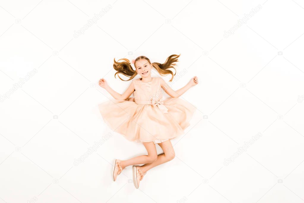 top view of happy child looking at camera while flying on white