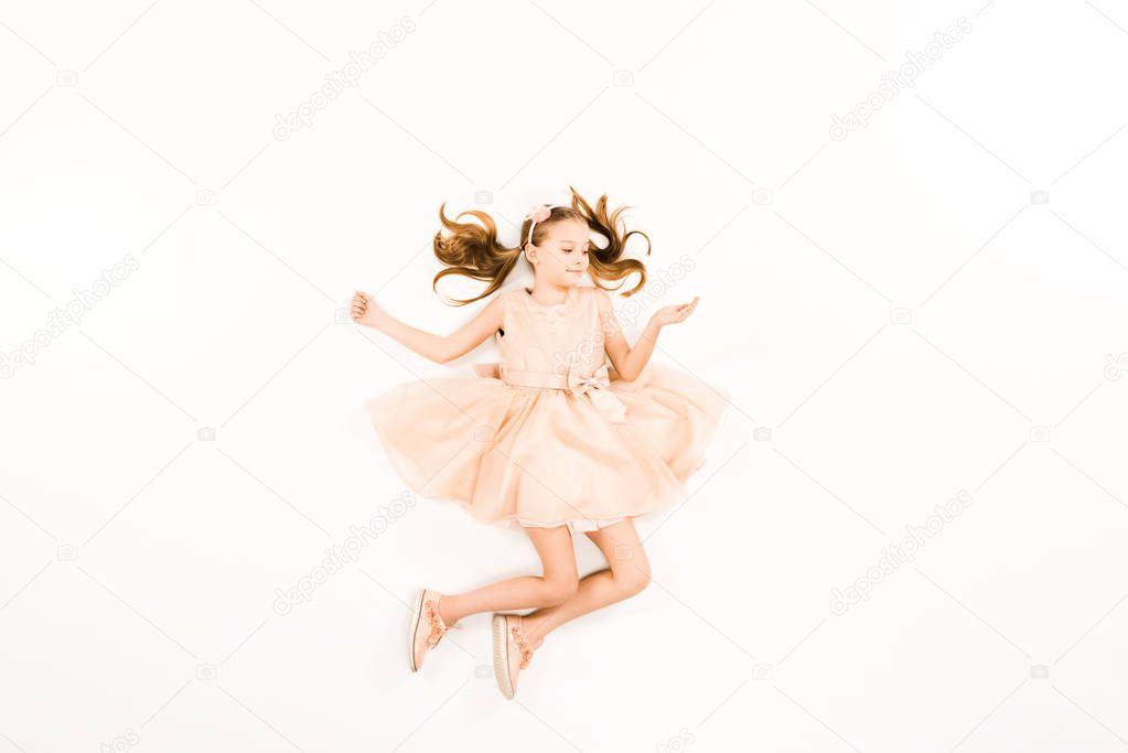top view of happy child in pink dress smiling while flying on white