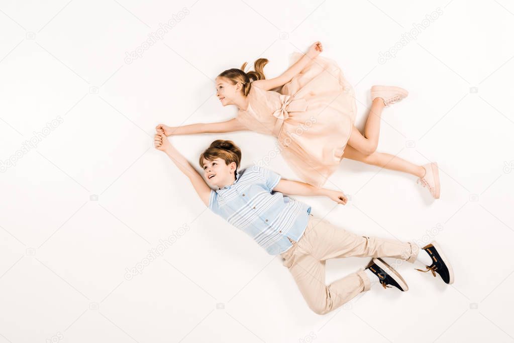 top view of adorable kids smiling while flying on white 