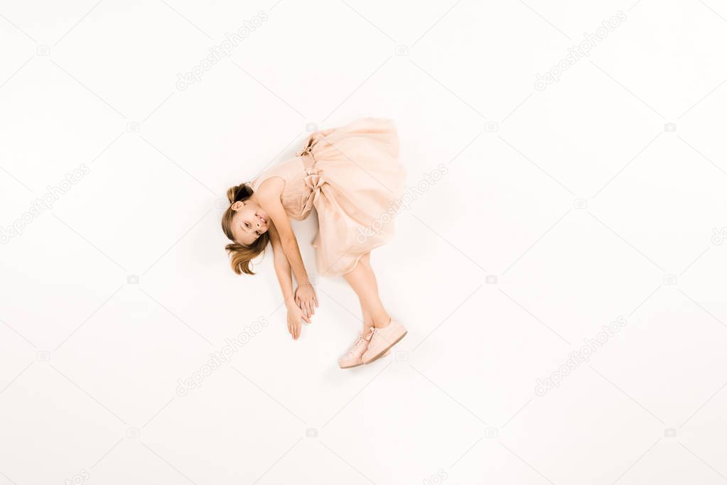 top view of adorable kid in dress looking at camera on white