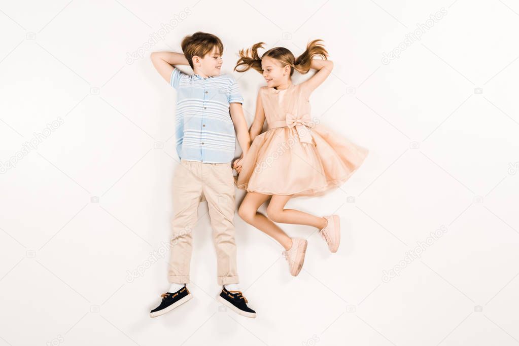 top view of cheerful kids looking at each other on white 