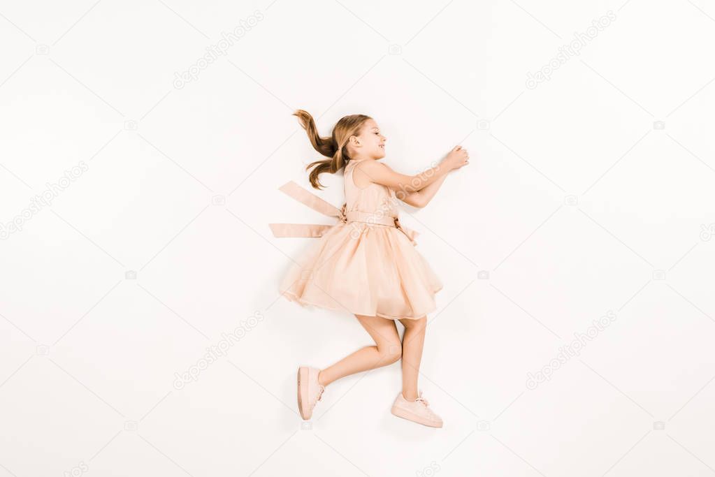 cute kid smiling and gesturing while lying on white 