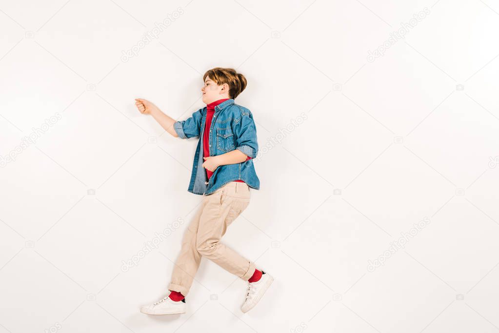 top view of adorable kid gesturing while lying on white 