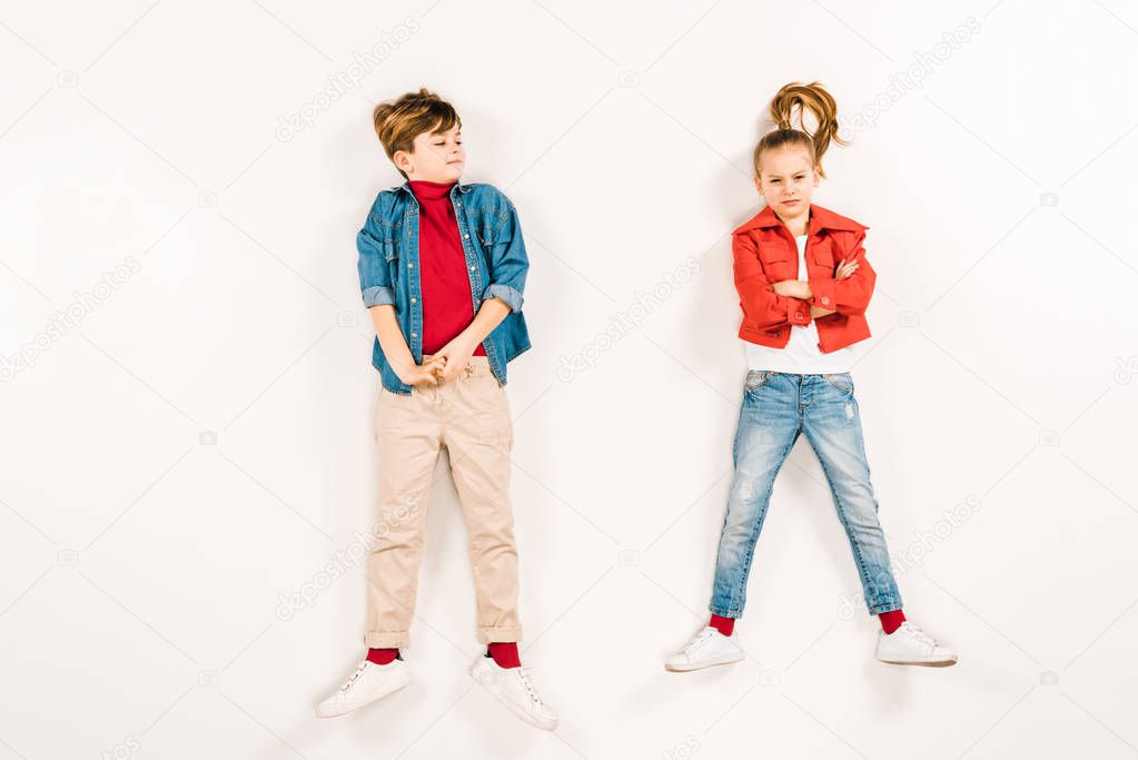 top view of kid looking at friend with crossed arms lying on white 