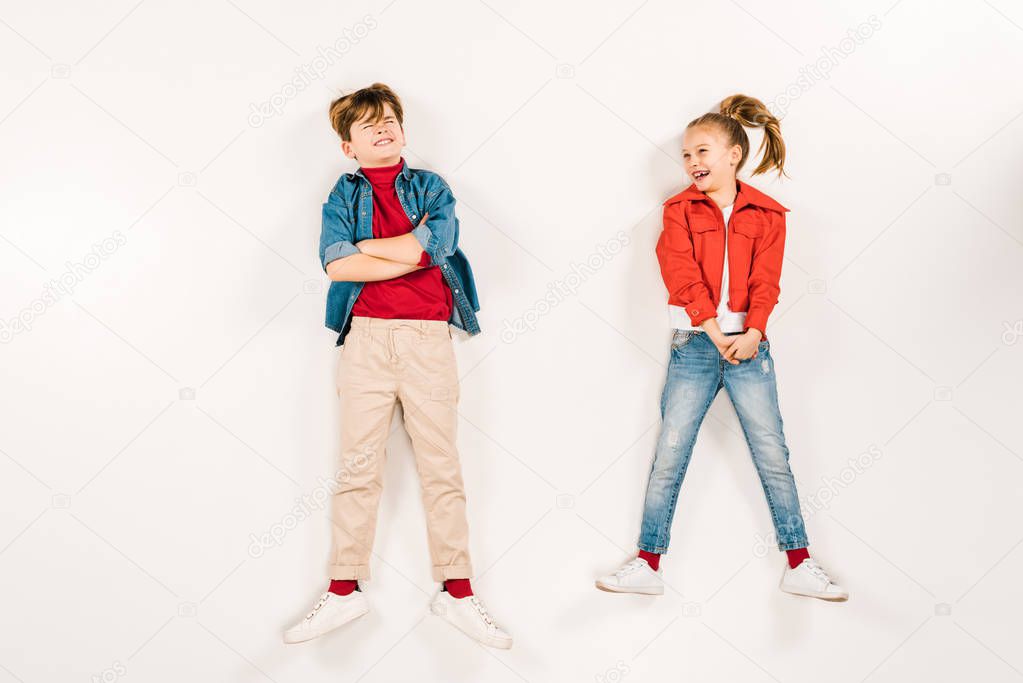 top view of cheerful kid near friend with crossed arms on white 