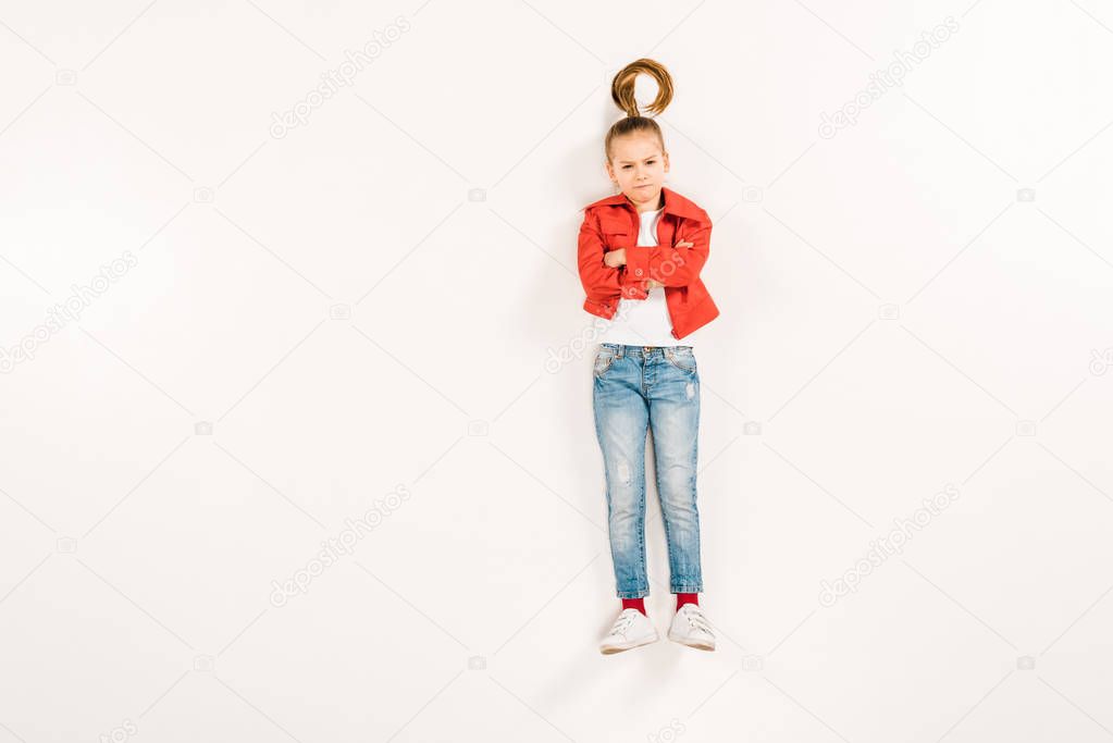 top view of displeased kid with crossed arms on white 