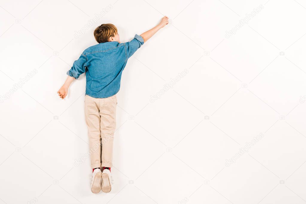 top view of kid lying and gesturing on white 