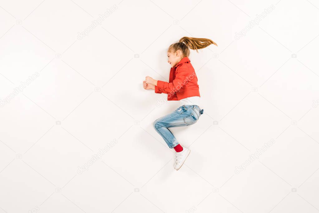 top view of cheerful kid in blue jeans gesturing on white 