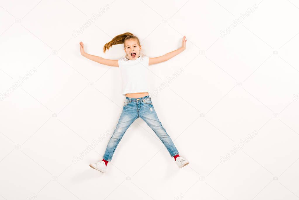 top view of scared kid screaming while lying on white 