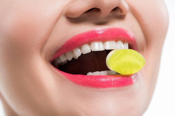 cropped view of happy girl eating yellow jelly candy isolated on white 